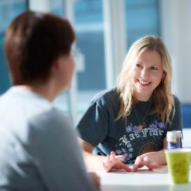 Woman smiling at another woman across meeting table