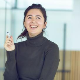 Woman smiling by whiteboard with marker in hand