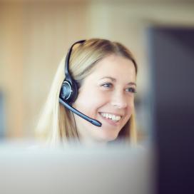 Woman with headset smiling in front of monitor