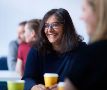 Woman smiling with cup of coffee in meeting
