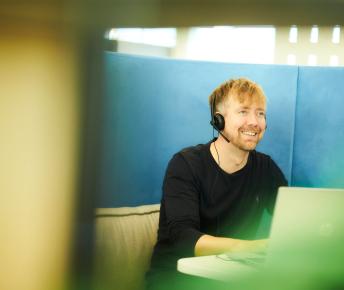 Seated man smiling with headset and laptop