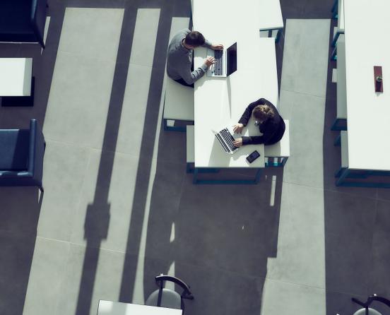 Birdseye photo of two people sitting at desks on their laptops