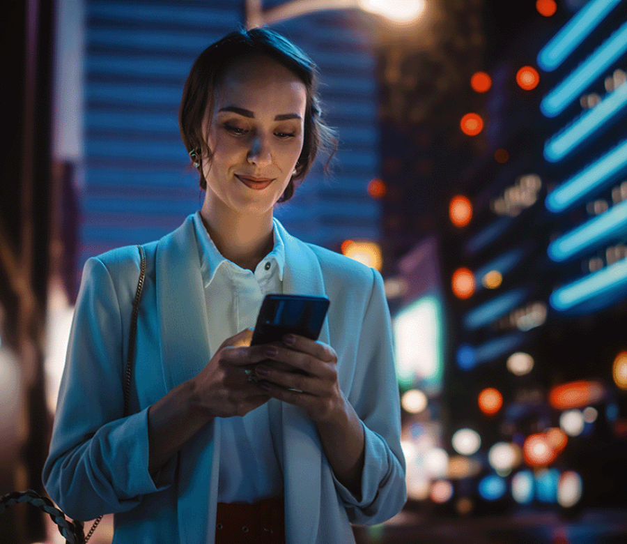 woman looking at phone in city at night